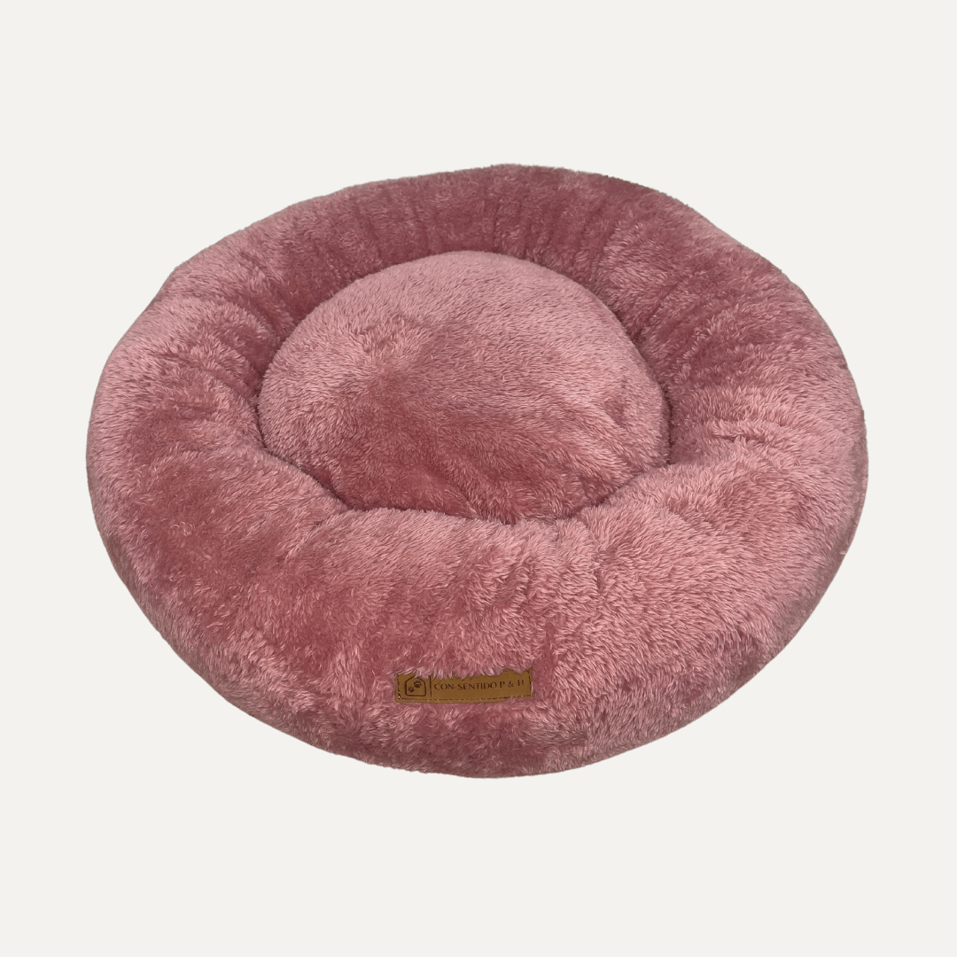 Cama Dona Ceiba antiestrés para perros y gatos en color rosado, diseñada con bordes elevados y materiales suaves para ofrecer un descanso cómodo.