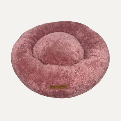 Cama Dona Ceiba antiestrés para perros y gatos en color rosado, diseñada con bordes elevados y materiales suaves para ofrecer un descanso cómodo.