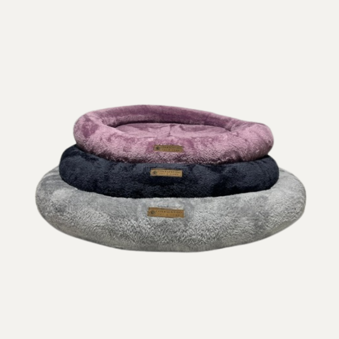 Cama Dona Roble para perros y gatos en colores rosado, azul y gris, diseñada con centro ortopédico de espuma, tela suave y diseño de bordes elevados que ayuda a mejorar el descanso de tus mascotas.